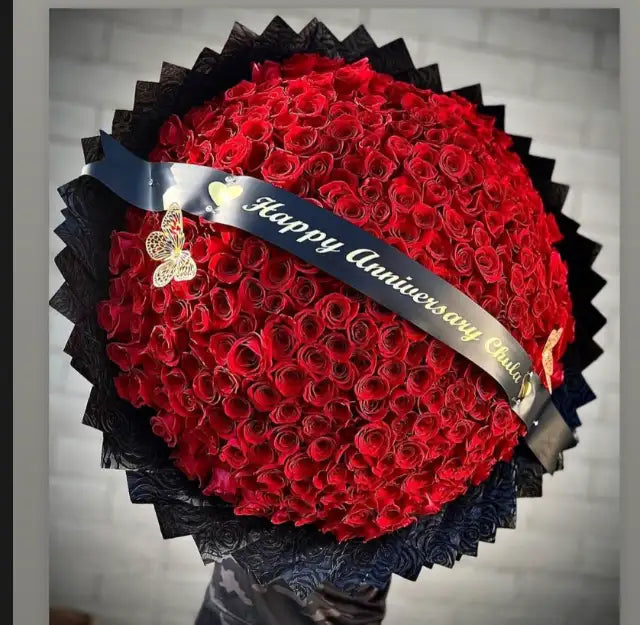 300 red roses with a black satin banner reading Happy Anniversary and a gold butterfly